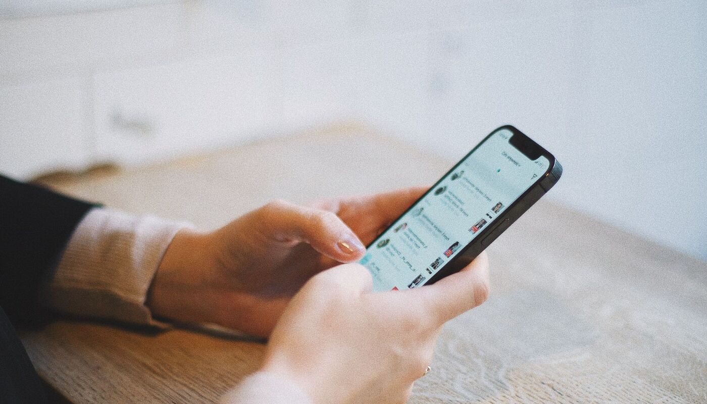 A hand holding a phone showing a news story