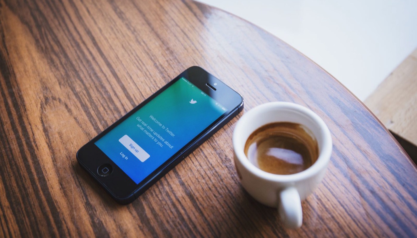 A smartphone showing a news app beside a cup of coffee on a table