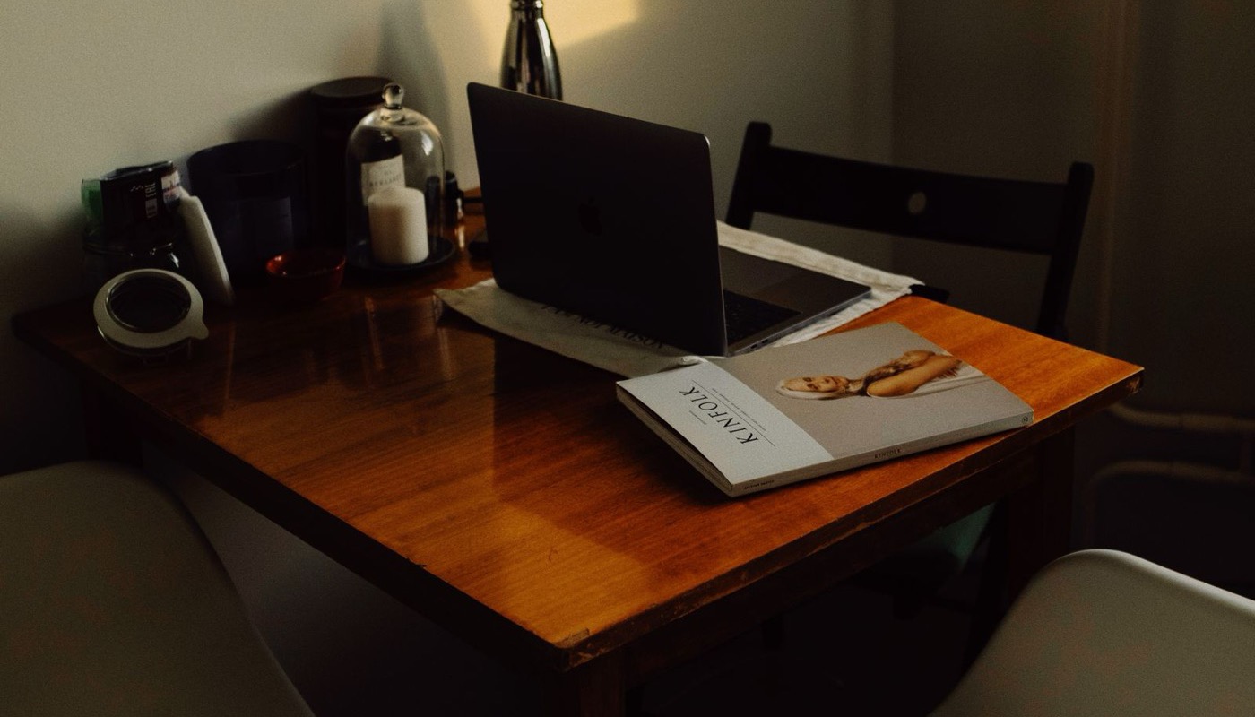 A laptop and notebook on a wooden desk in a home workspace