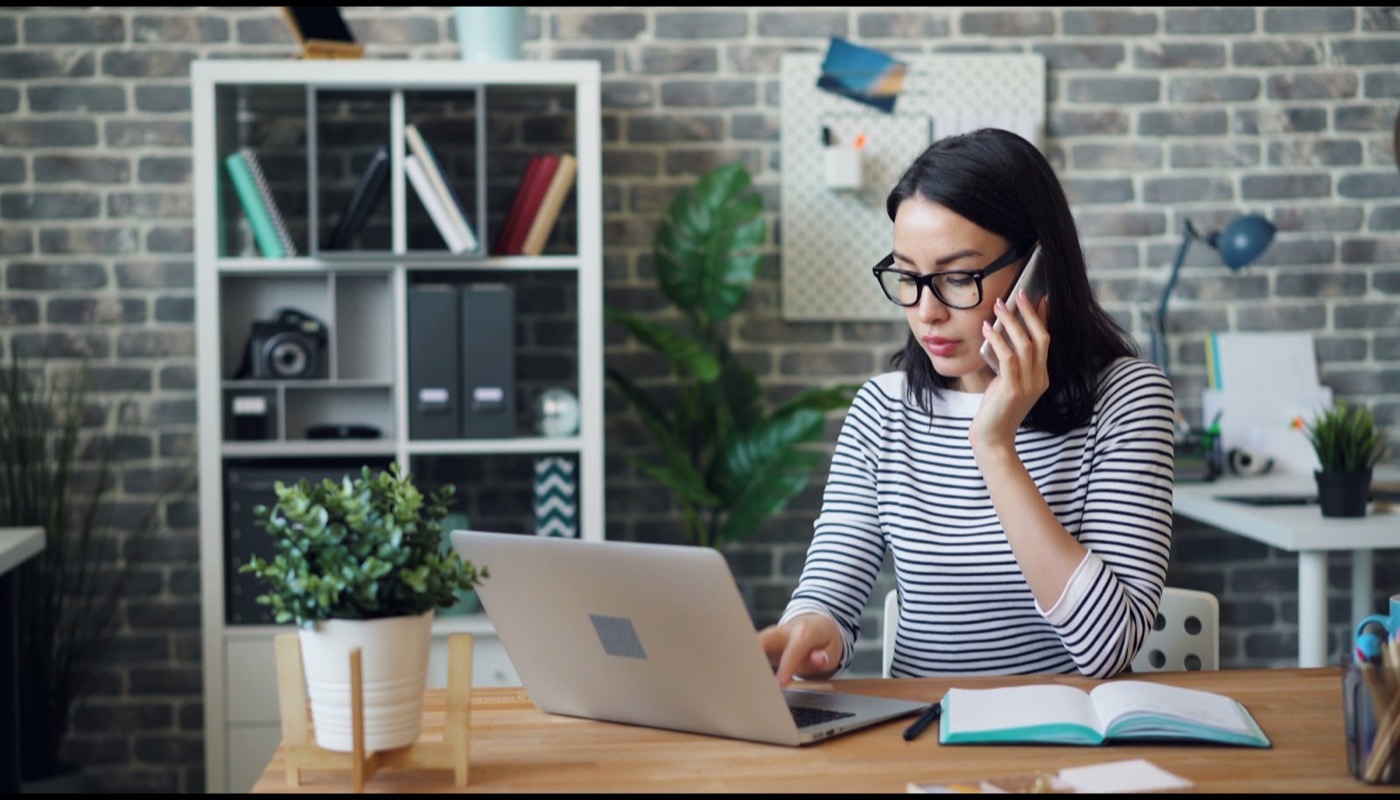 A person working at a laptop with a notebook at a desk