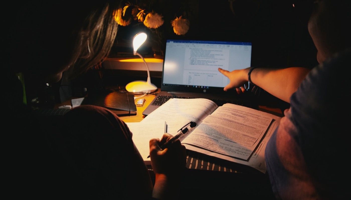 Two students studying together at a laptop with handwritten notes
