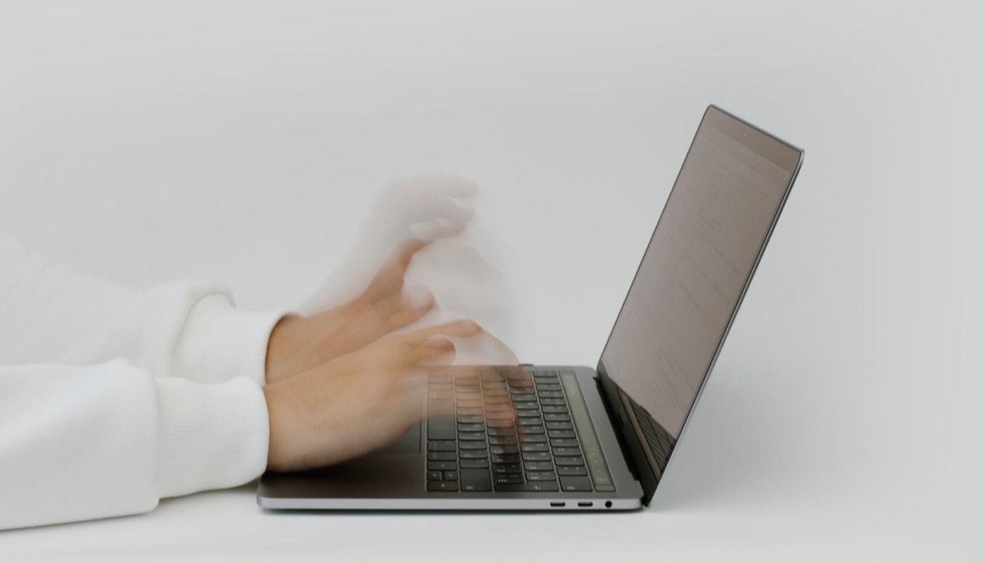 Close-up of hands typing on a laptop keyboard