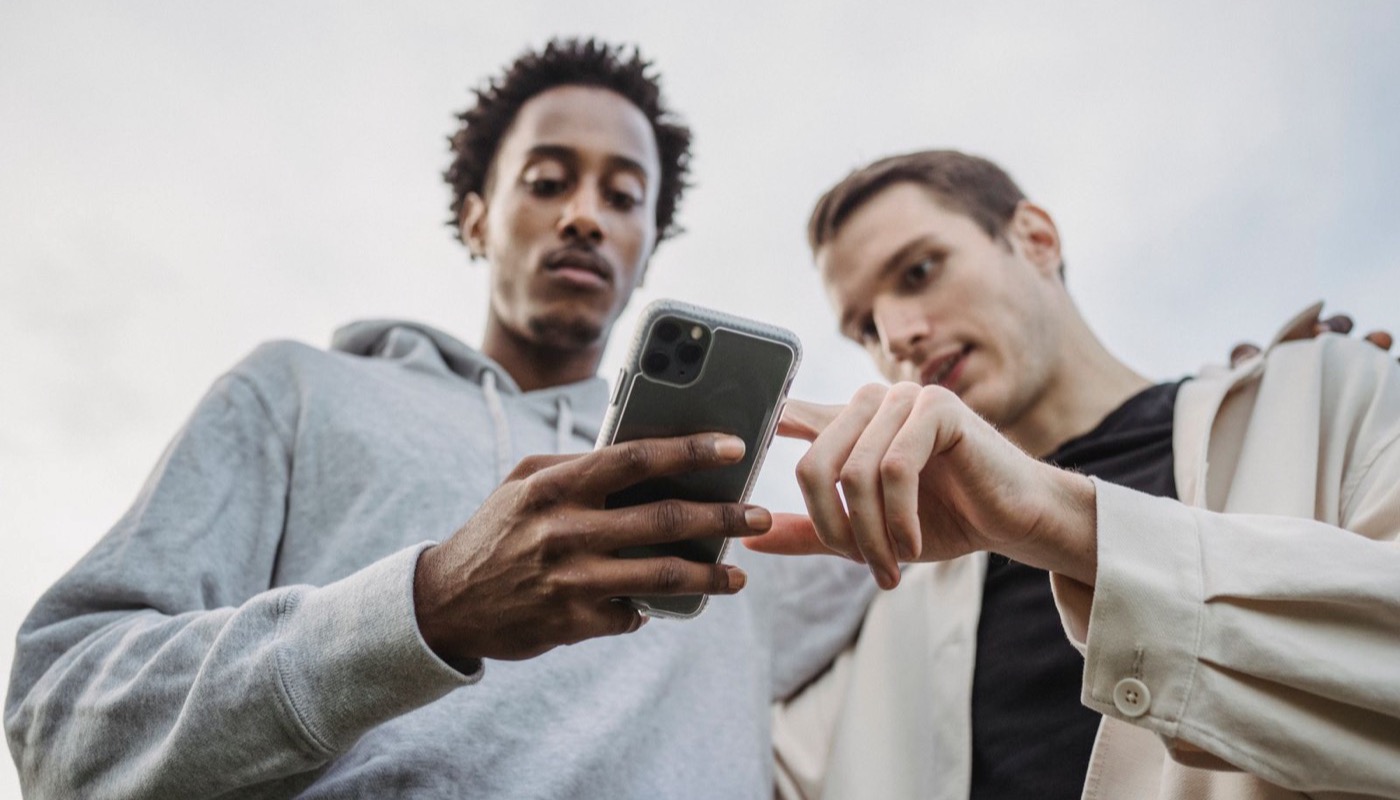 Two young people looking at news on a phone outdoors