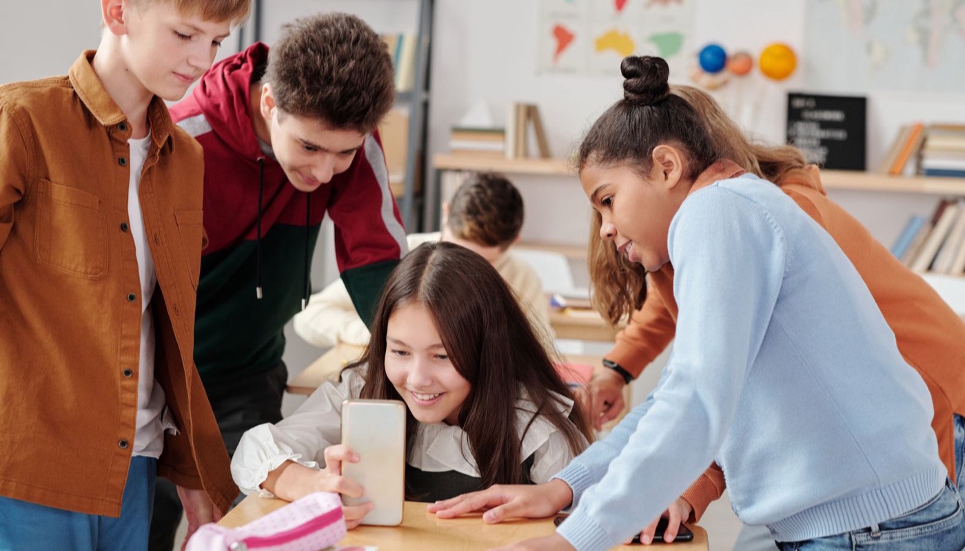 A group of young people looking at a phone together